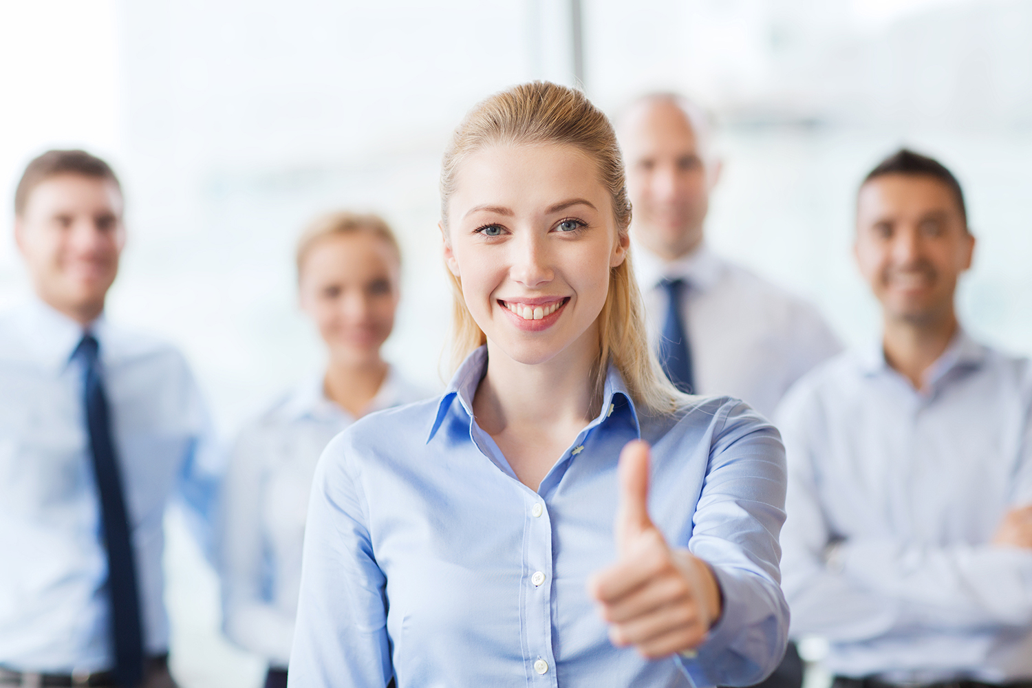 business, people, gesture and teamwork concept - smiling businesswoman showing thumbs up with group of businesspeople in office